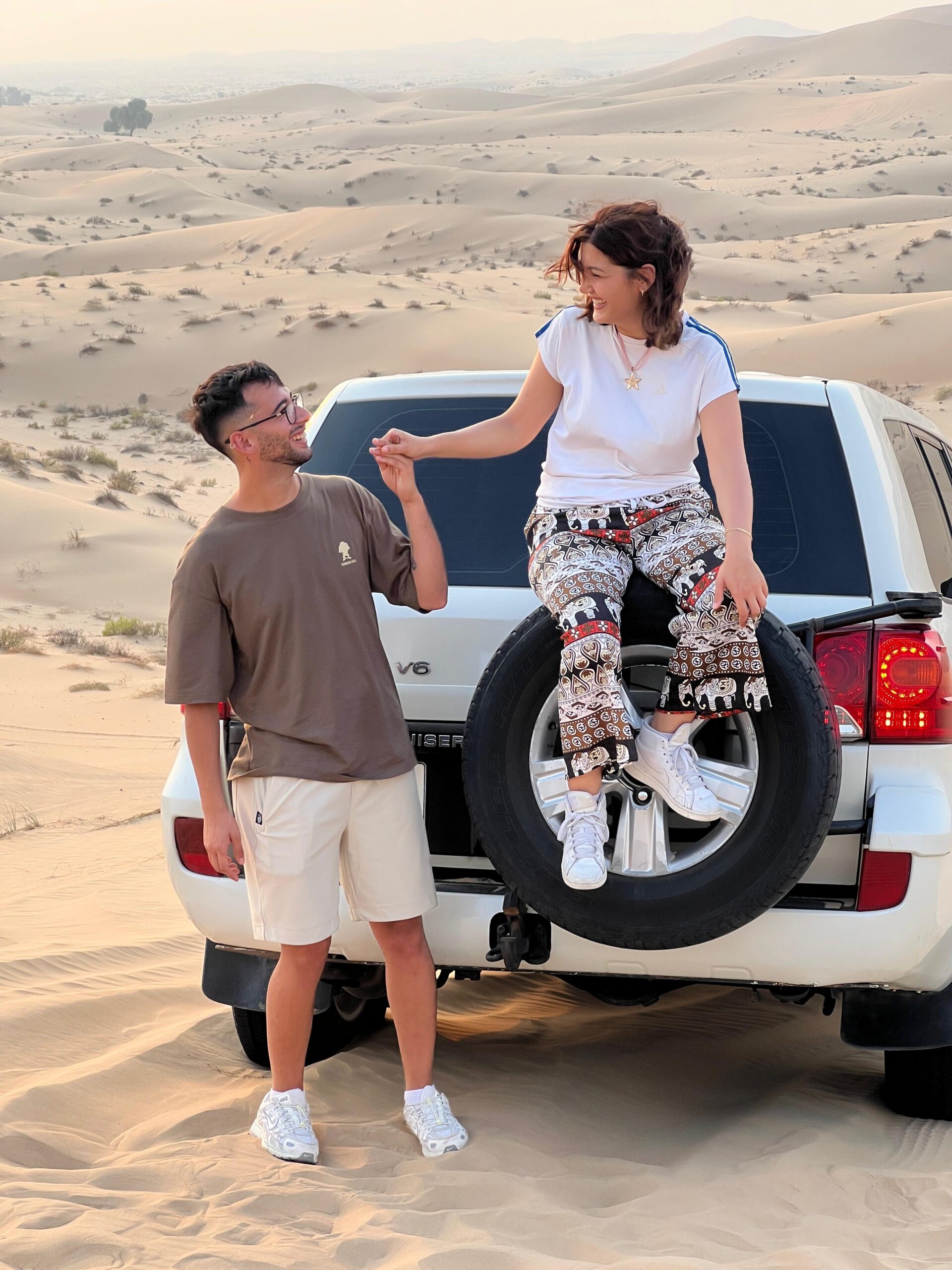 Tourists enjoying a peaceful camel ride against a breathtaking desert sunset in Dubai