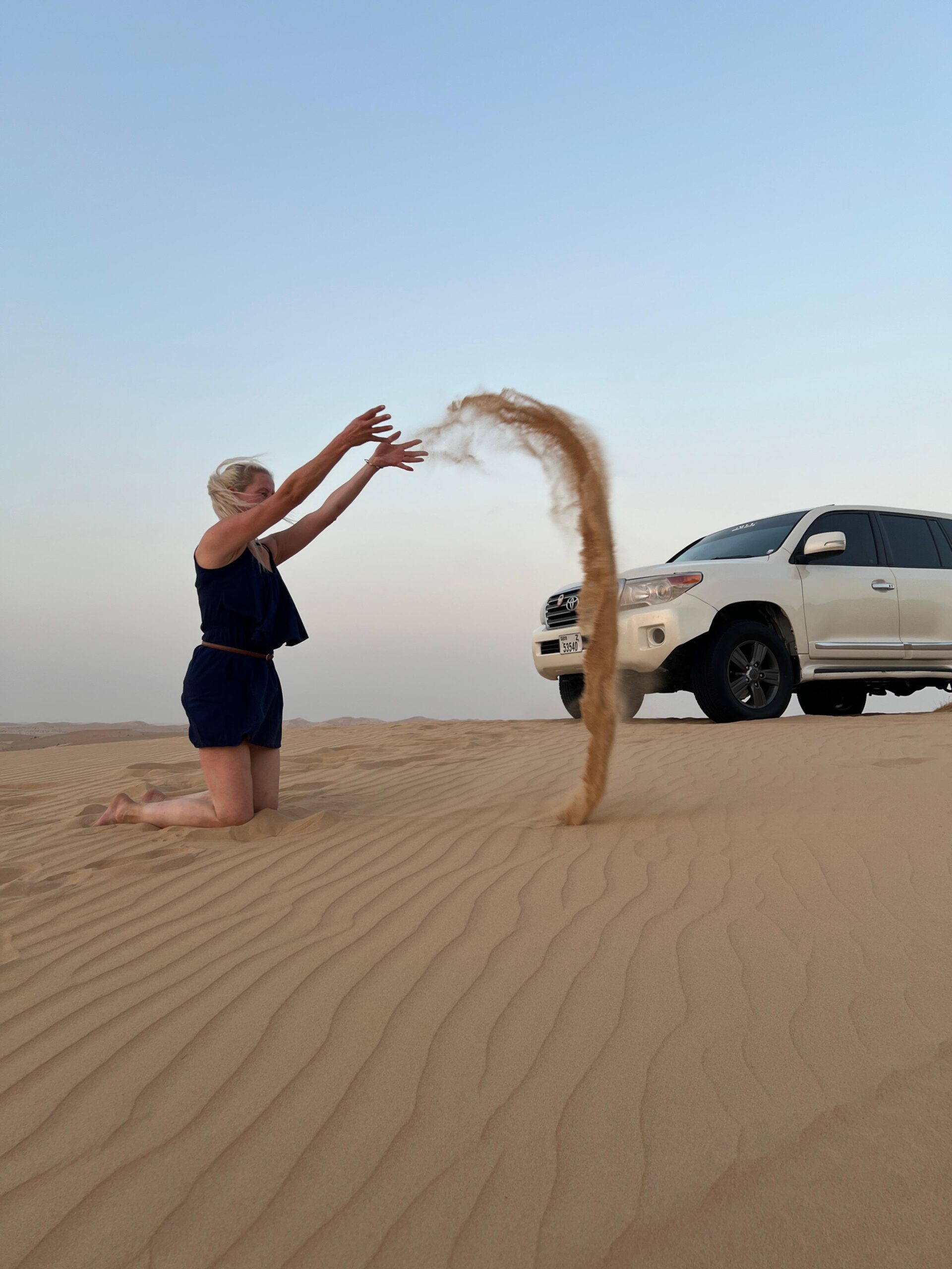 A wide panoramic photograph showcasing the vast, endless dunes of the Abu Dhabi desert